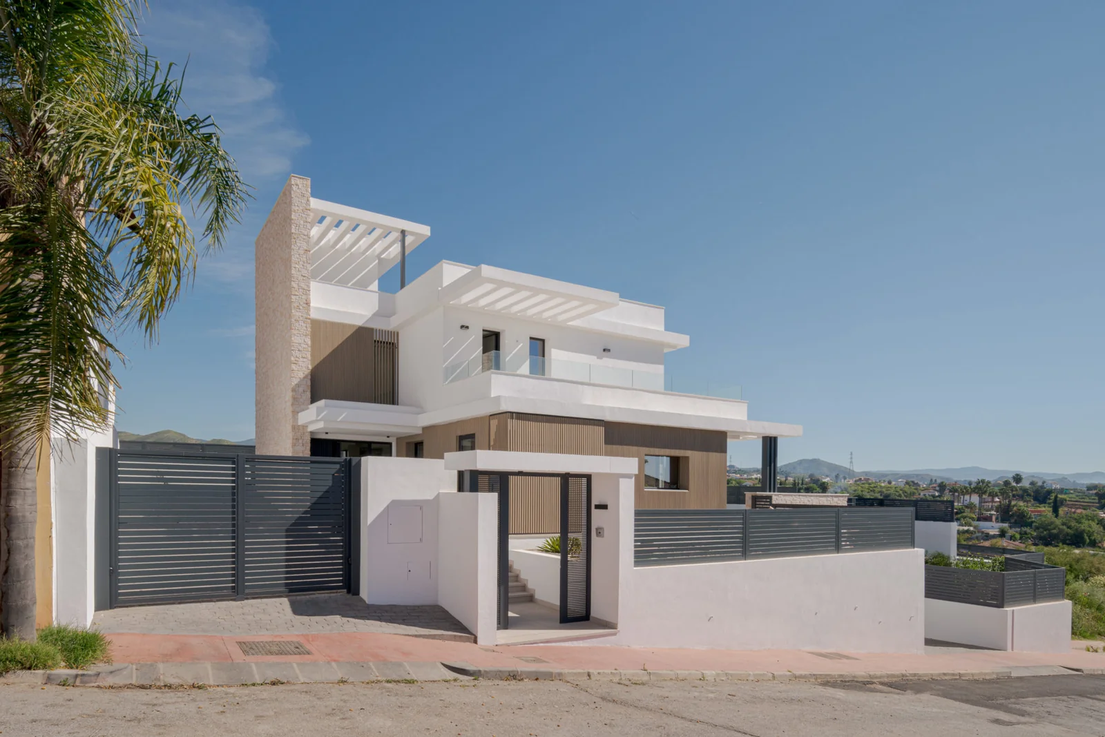 Villa Venetta vista desde la calle: volúmenes blancos, celosía de madera y la sierra al fondo